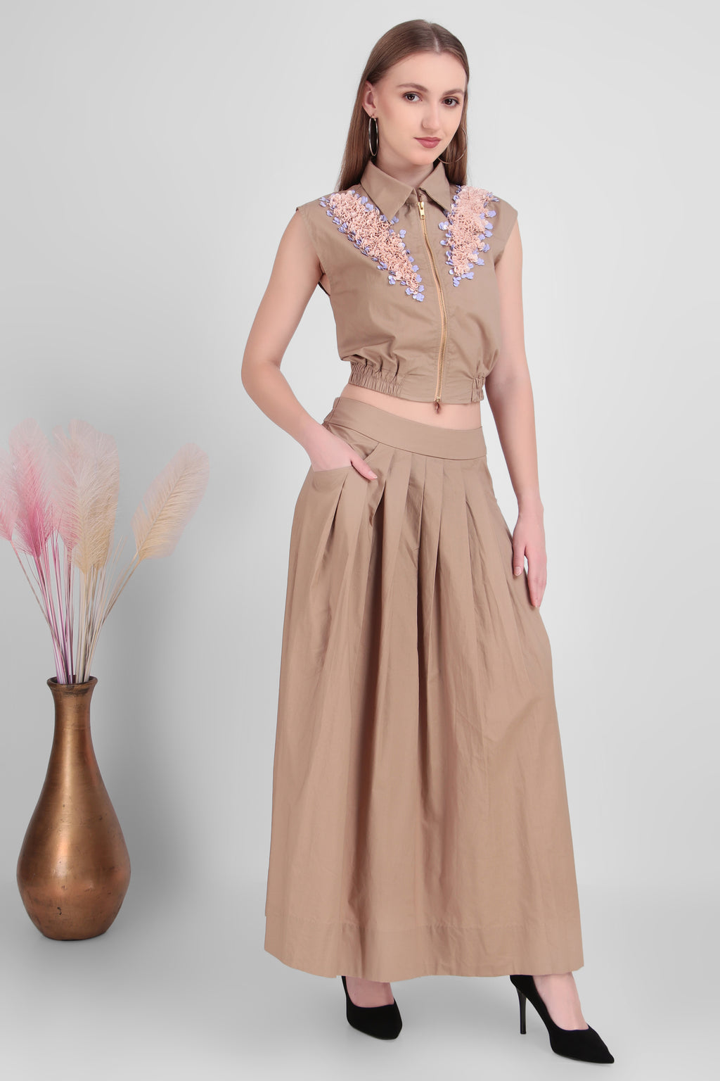 Woman wearing a beige outfit with floral embroidery on a white background